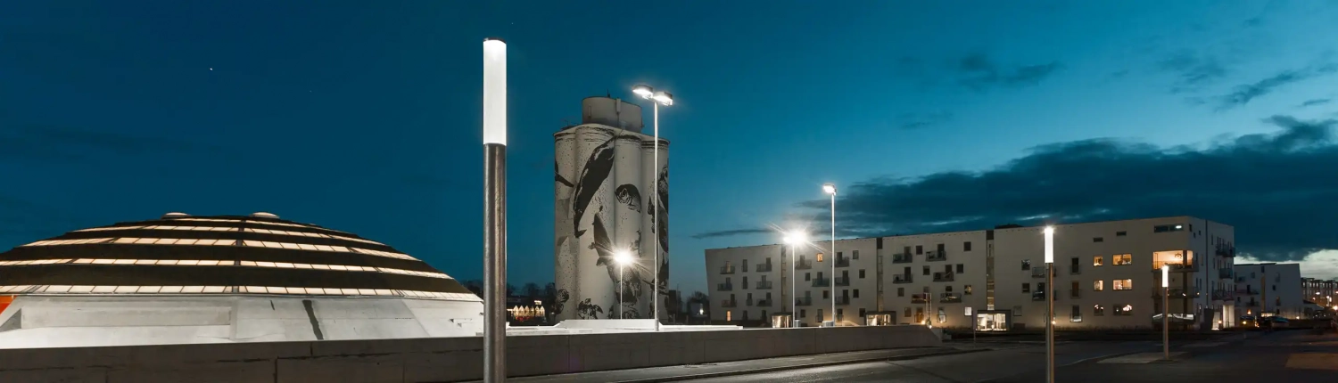 Eine Straßenlampe vor einer modernen Wohngegend bei Sonnenuntergang.