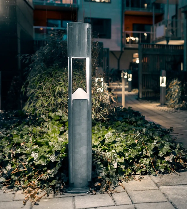 Eine moderne Außenleuchte entlang eines Weges, umgeben von grüner Vegetation.