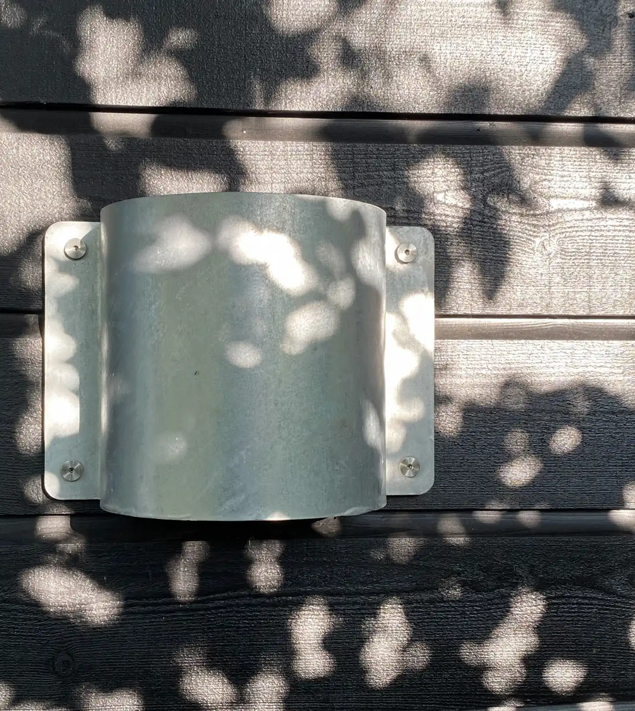 liber l5u wandleuchte 10 Eine metallische Wandlampe an einer dunklen Holzwand