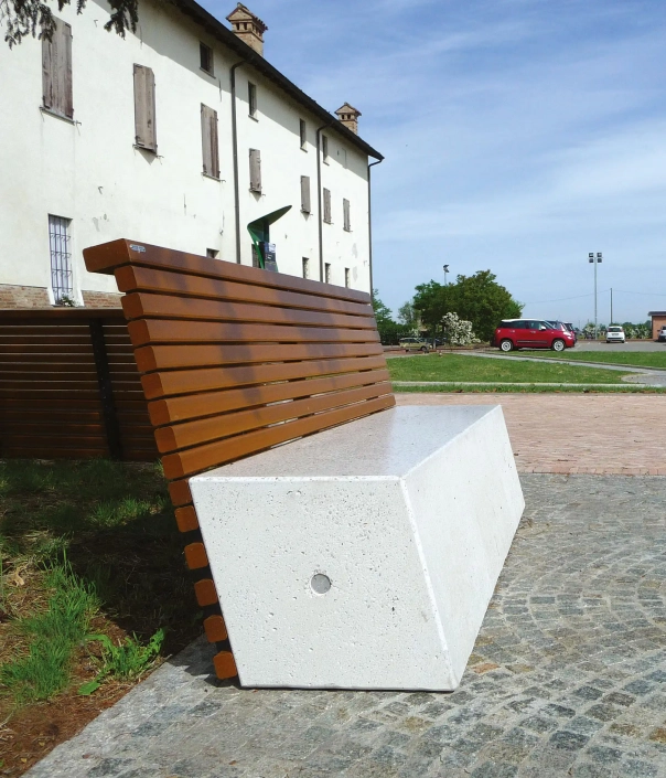 Eine moderne Outdoor-Bank mit einer Betonbasis und einer schrägen Rückenlehne aus horizontalen Holzlatten.