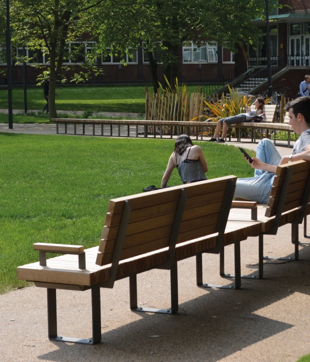 Holzbank mit Rückenlehne und Armlehne in einem Park.
