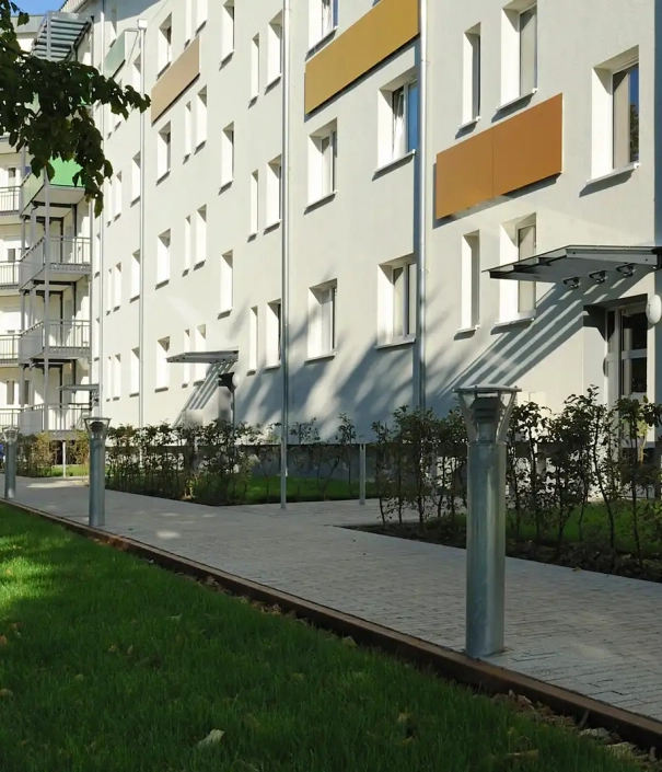 Modernes Wohngebäude mit Gehweg und Leuchten im Vordergrund.