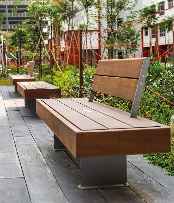 Moderne Sitzbank aus Holz und Metall mit Rückenlehne in einem urbanen Parkbereich.