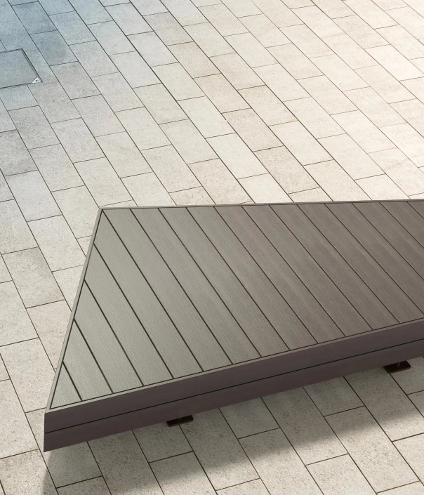 Trapezförmige Holzbank mit horizontalen Holzlatten auf hellem Pflasterboden.