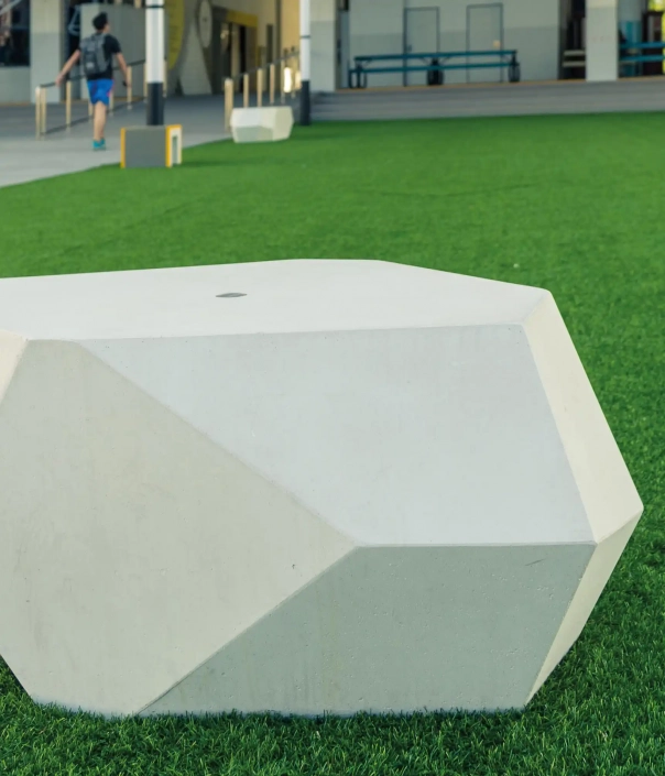 Moderne polygonale Betonbank auf einer Grünfläche in einem öffentlichen Raum.