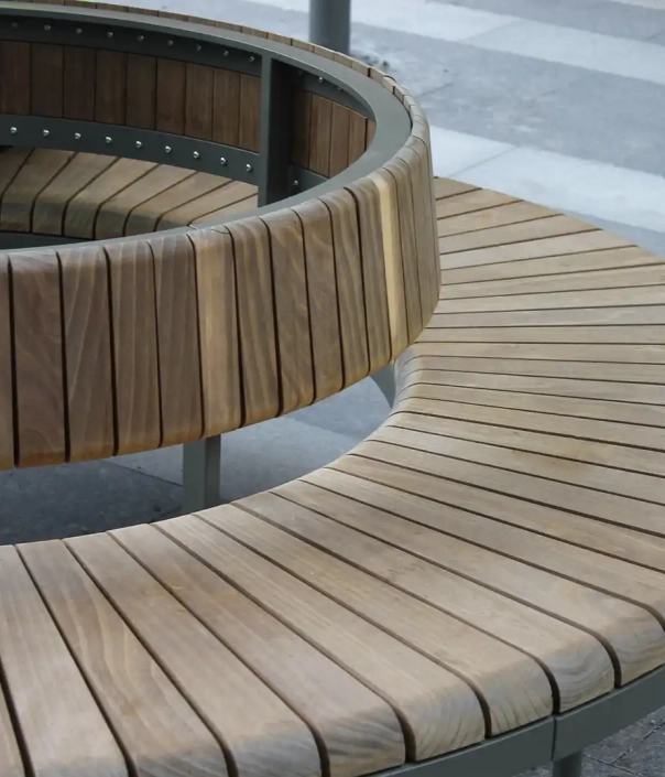 Runde Sitzbank aus Holz mit einer zusätzlichen Rückenlehne um einen Baum.