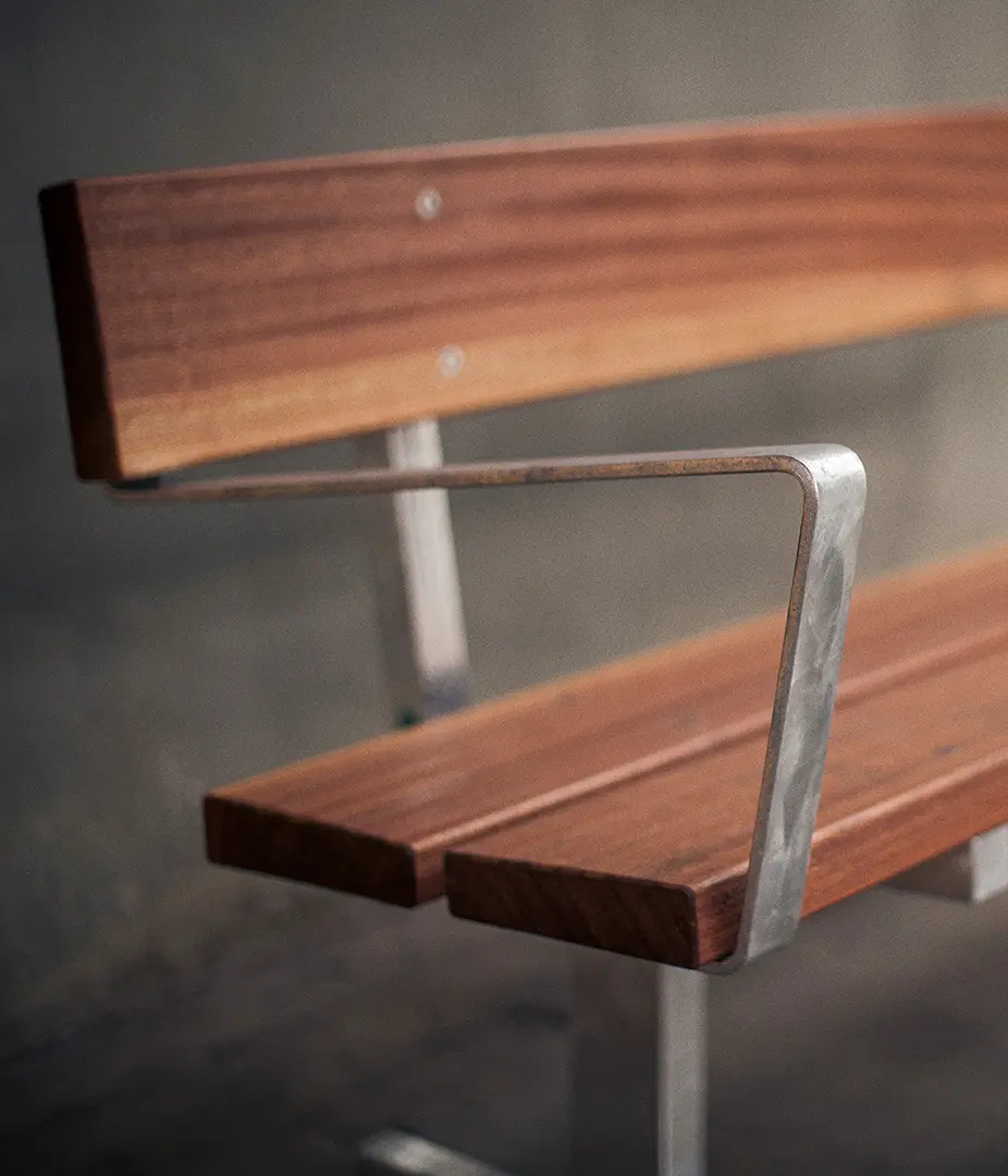 Detailaufnahme einer modernen Bank mit Holzlatten und einem metallischen Gestell.