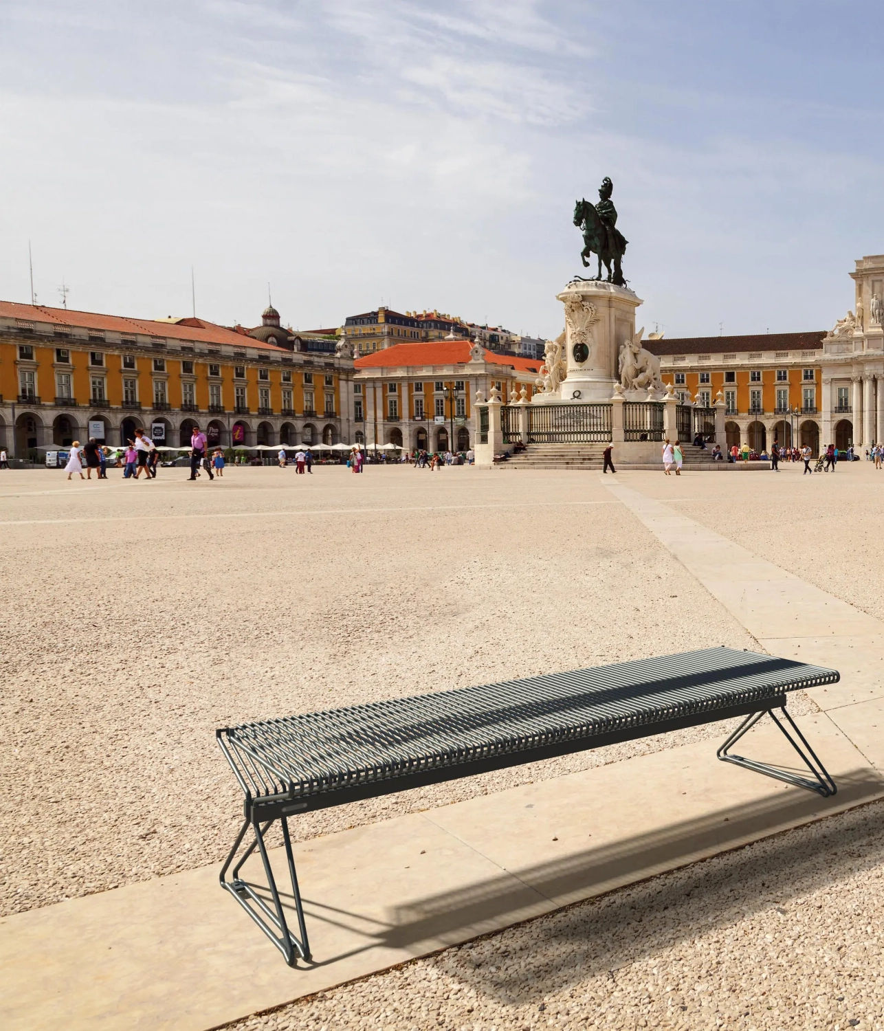 Moderne Parkbank aus Metall vor historischem Platz als Hintergrund.