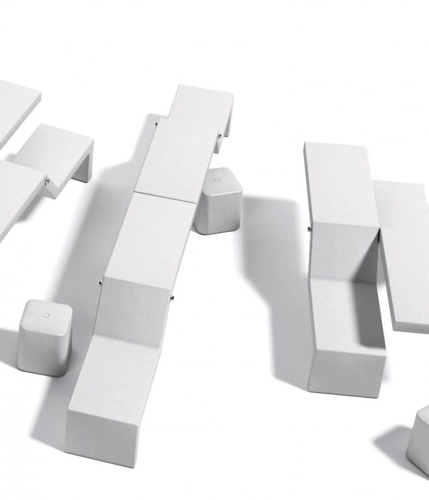 Eine Anordnung von modernen, weißen Betonmöbeln, darunter Sitzbänke und Tische in verschiedenen Höhen und Formen.