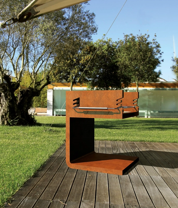 Alt-Text: Urbanes Einrichtungselement im Freien, eine moderne Grillstation aus Metall, umgeben von Rasen und einer begrünten Umgebung.