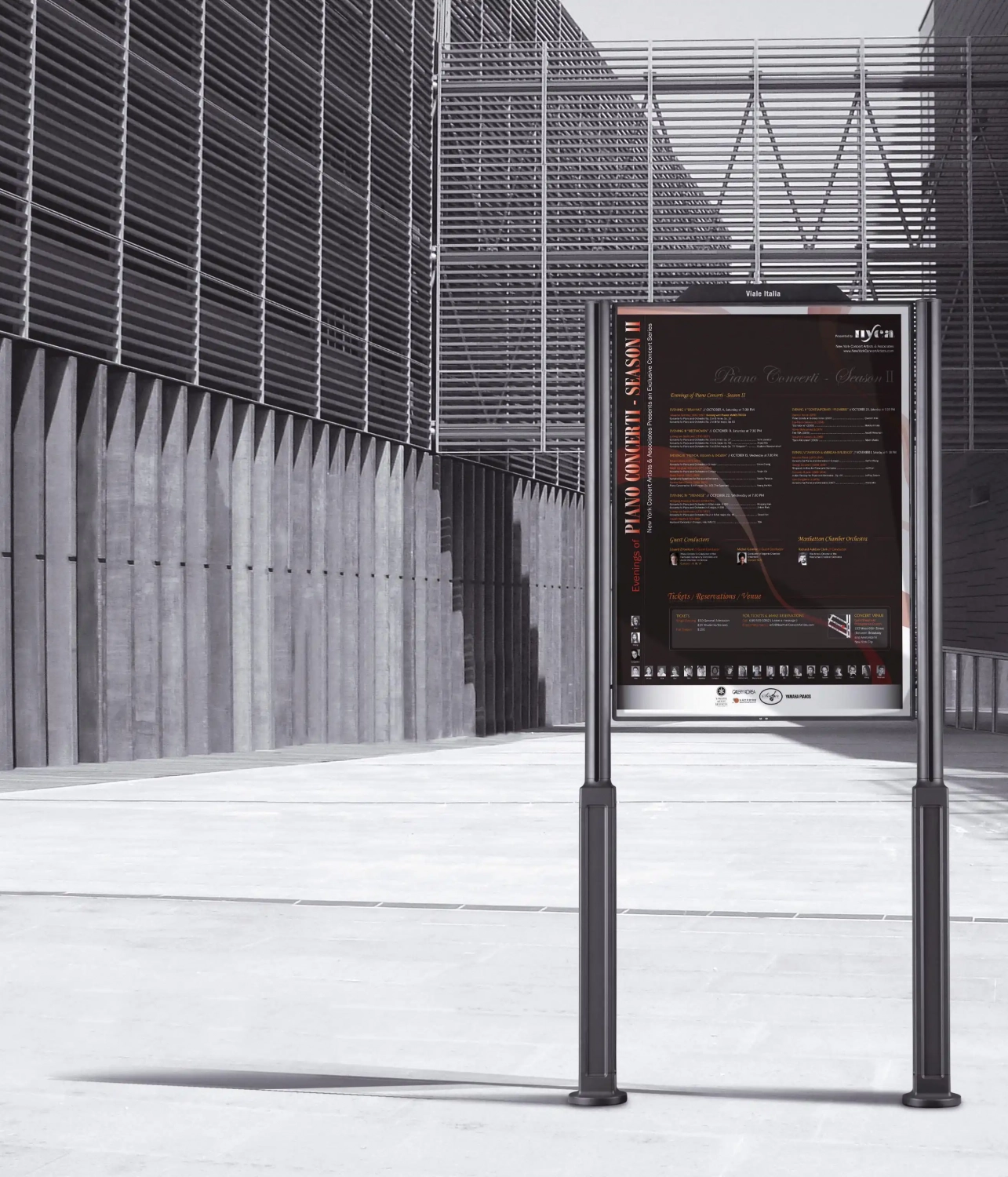 Modernes Hinweisschild, welches zwischen zwei Pfosten angebracht ist und vor einem modernen Gebäude steht.