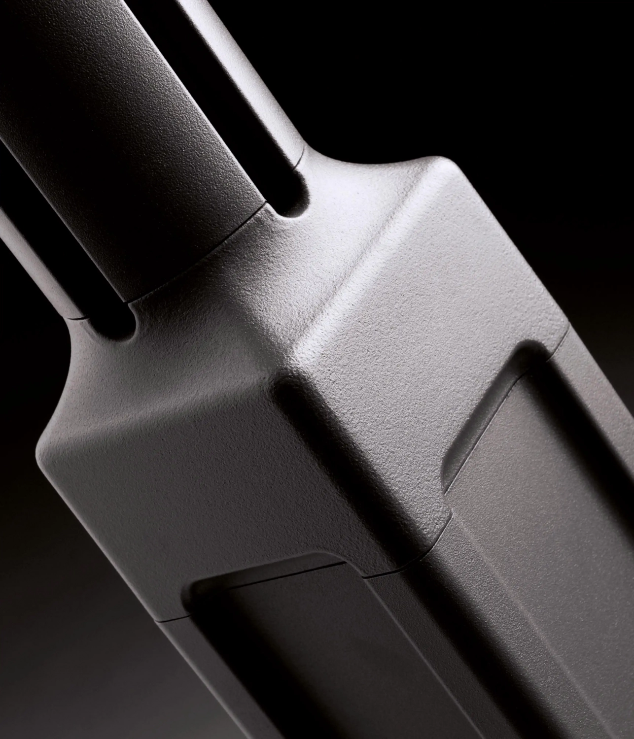 Alt-Text: Nahaufnahme eines schwarzen Hinweisschildes mit strukturiertem Design auf schwarzem Hintergrund.