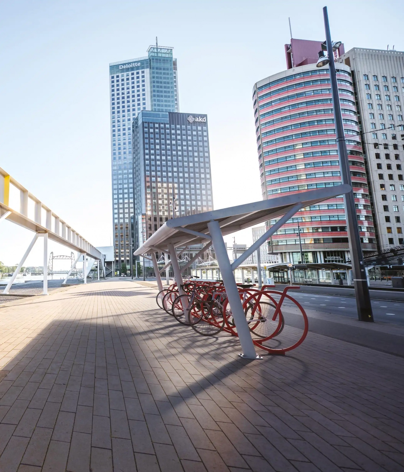 Alt-Text: "Moderne Überdachungen für Fahrräder in einer urbanen Umgebung mit Hochhäusern im Hintergrund."