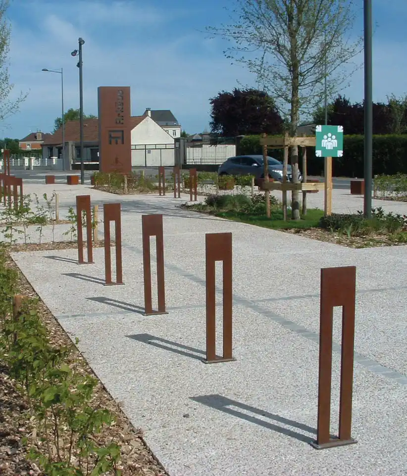 Alt-Text: "Eine moderne Radverkehrseinrichtung mit eleganten Fahrradständern und einer Reifenpumpe in einem begrünten Bereich."