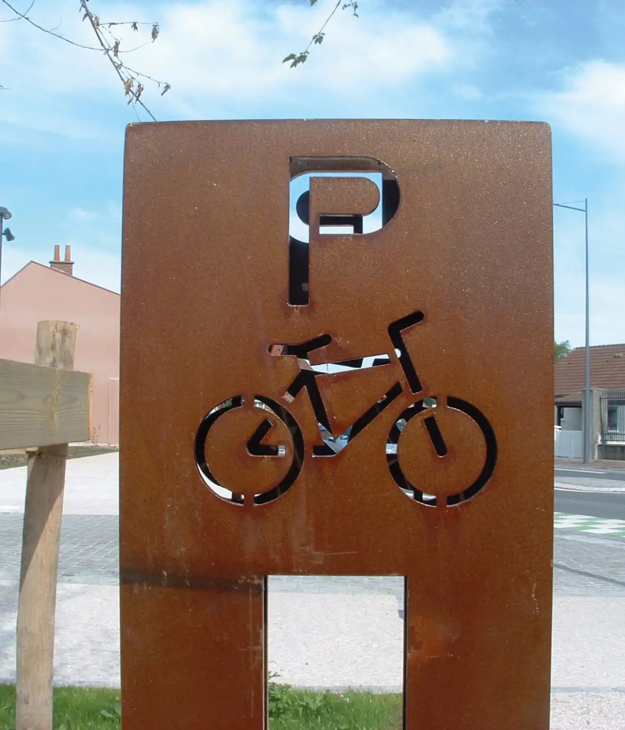 Alt-Text: „Metallschild mit Fahrrad-Symbol und Parkhinweis für Radfahrer in einer städtischen Umgebung.“