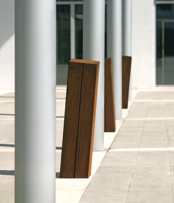 Moderner Stahlpoller steht auf einem gepflasterten Boden, flankiert von eleganten Säulen."