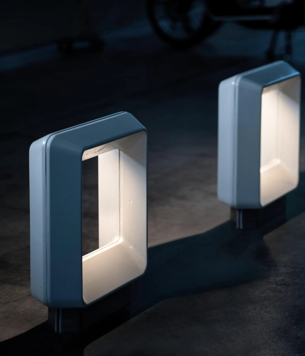 Zwei moderne Poller mit integrierter Beleuchtung, die in einer dunklen Umgebung aufgestellt sind.