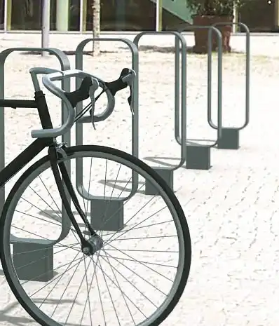 Alt-Text: "Ein modernes Fahrrad steht neben mehreren Fahrradständern auf einem gepflasterten Platz."