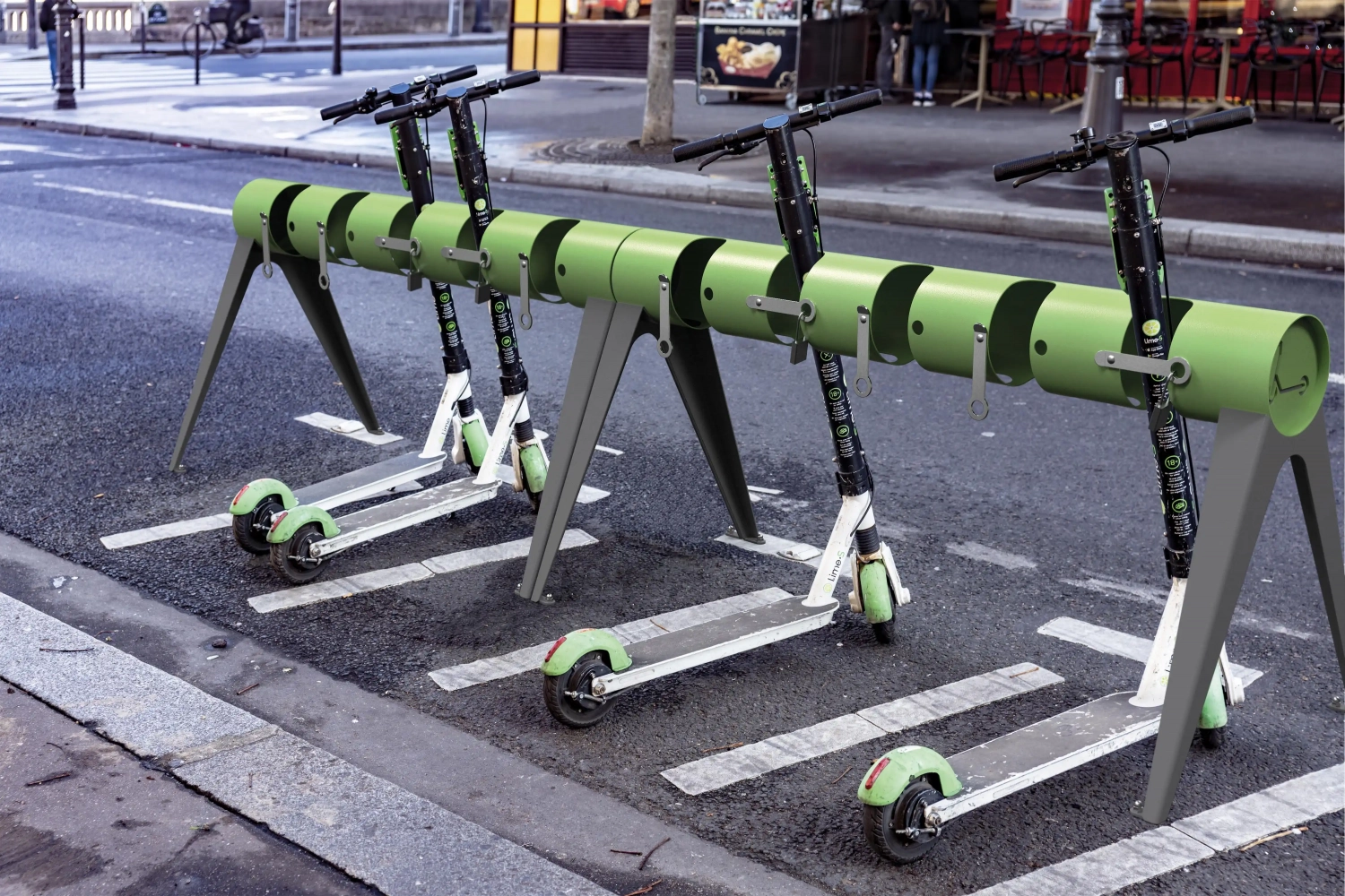 Alt-Text: Fahrradständer für E-Scooter auf einer Straße, mit mehreren abgeparkten grünen Scootern.