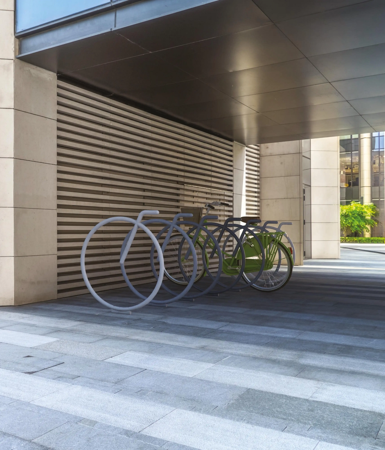 Alt-Text: "Moderne Fahrradständer aus Metall in einem urbanen Umfeld, auf einem gepflasterten Boden unter einem überdachten Bereich."