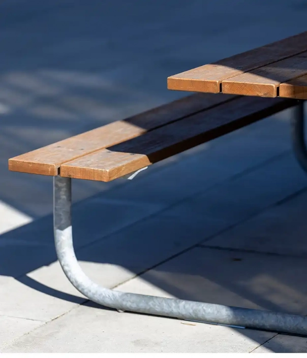 Alt-Text: Detailansicht einer urbanen Sitzgruppe aus Holz und Metall, die Teil eines öffentlichen Innenraums ist.