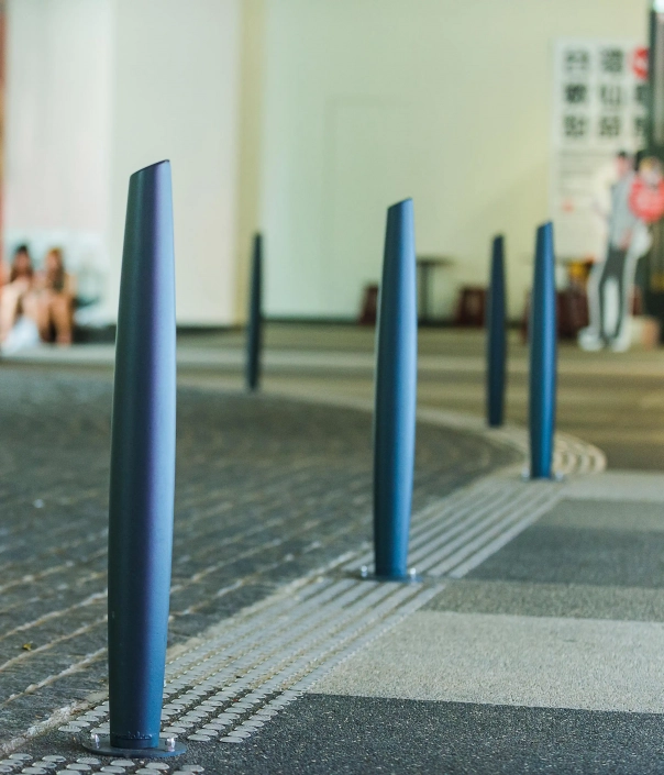 Serie von eleganten, blauen Pollern auf einem gepflasterten Boden in einer modernen Umgebung.