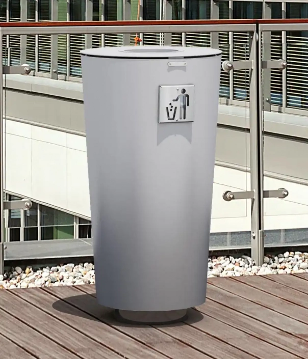 Ein runder Abfallbehälter in einer leicht konischen Form aus Metall, welcher auf einem Holzdeck steht.