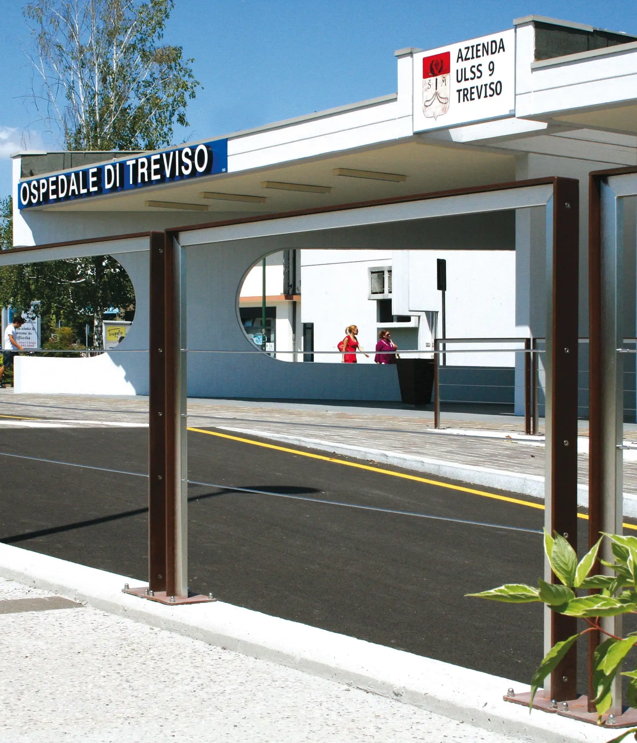 Alt-Text: "Ein Bild von Absperrungen am Eingang des Ospedale di Treviso, mit einer klaren Sicht auf die Straße und umliegende Gebäude."